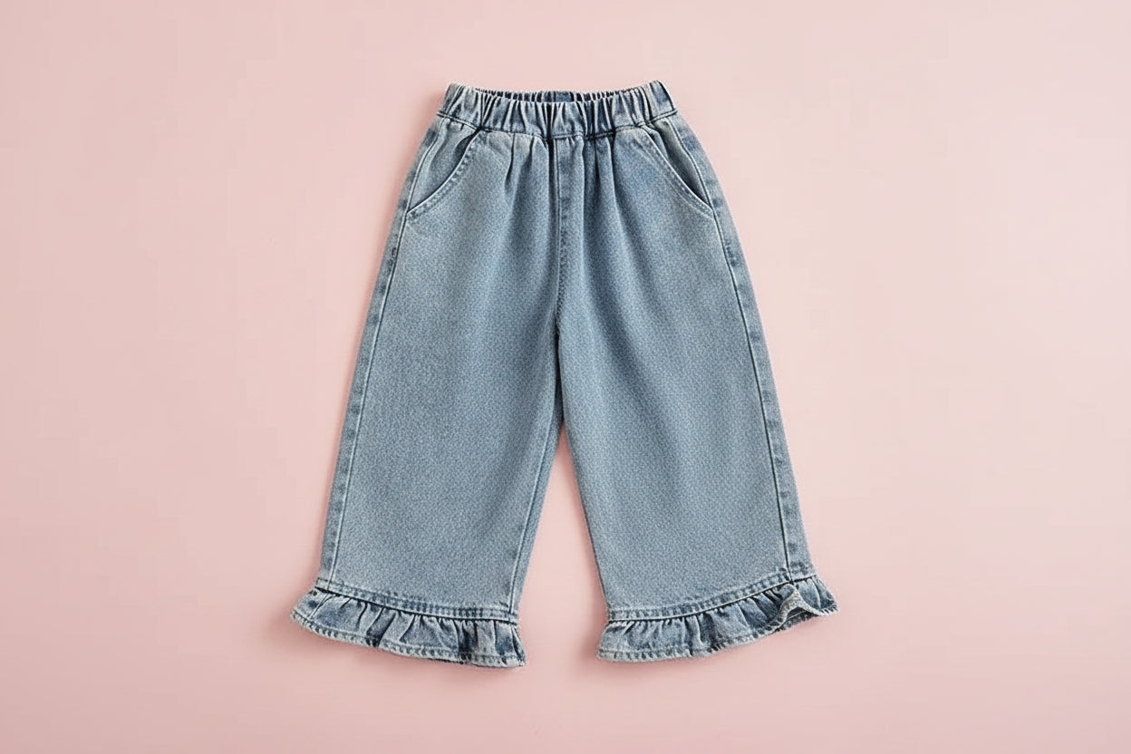 Denim skirt with ruffled hem on a wooden table with a cup and bread in the background.